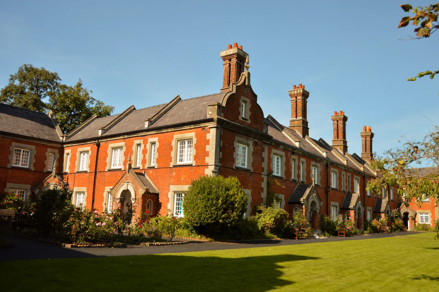 St John's Winchester almshouses: a red-brick terrace with tall chimneys behind a lawn